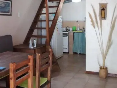Planta baja con mesa, cocina y escalera de madera