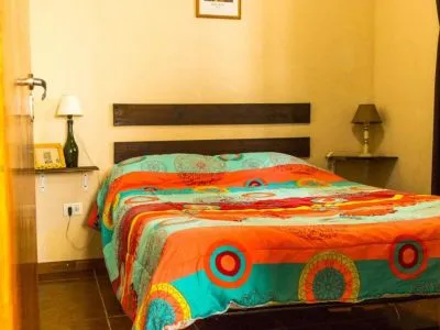 Dormitorio con cama doble y acolchado colorido en Cabaña 2